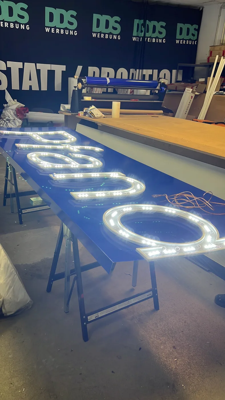 Geöffnete Leuchtbuchstaben mit eingeschalteten LED-Modulen auf der DDS-Werkbank
