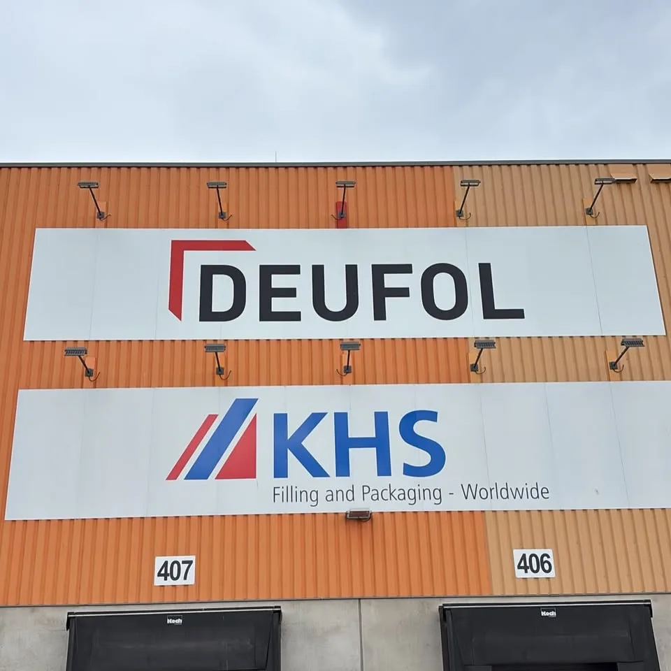 Firmenschilder DEUFOL und KHS an einer orangefarbenen Hallenfassade