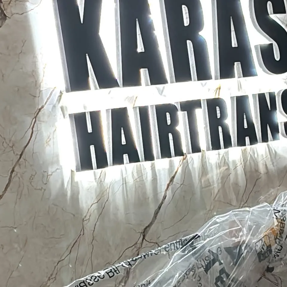 Plastische Buchstaben Karas Hairtrans auf einer hellen Innenwand