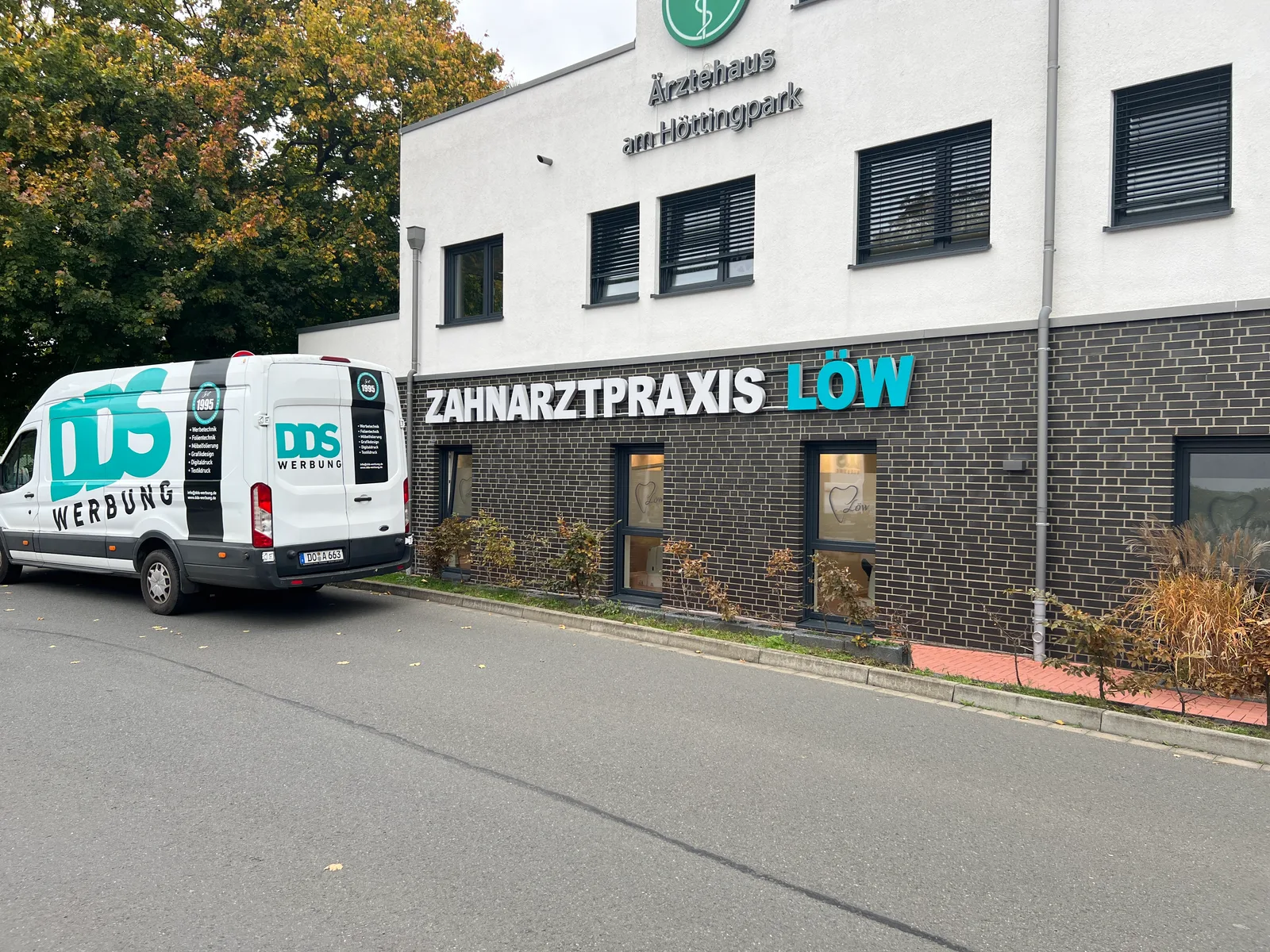Fassadenschriftzug der Zahnarztpraxis Löw mit DDS-Montagefahrzeug